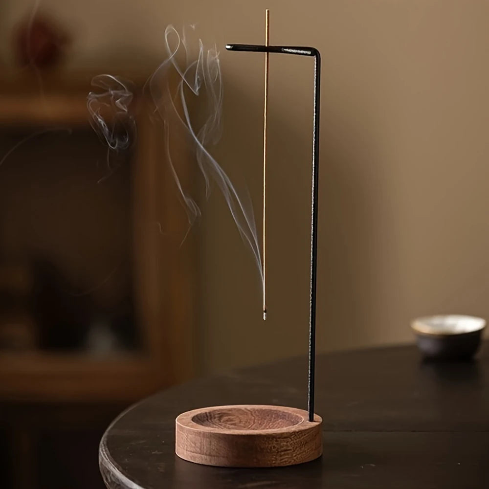 Incense stick holder with incense burning on a wooden base against a blurred background