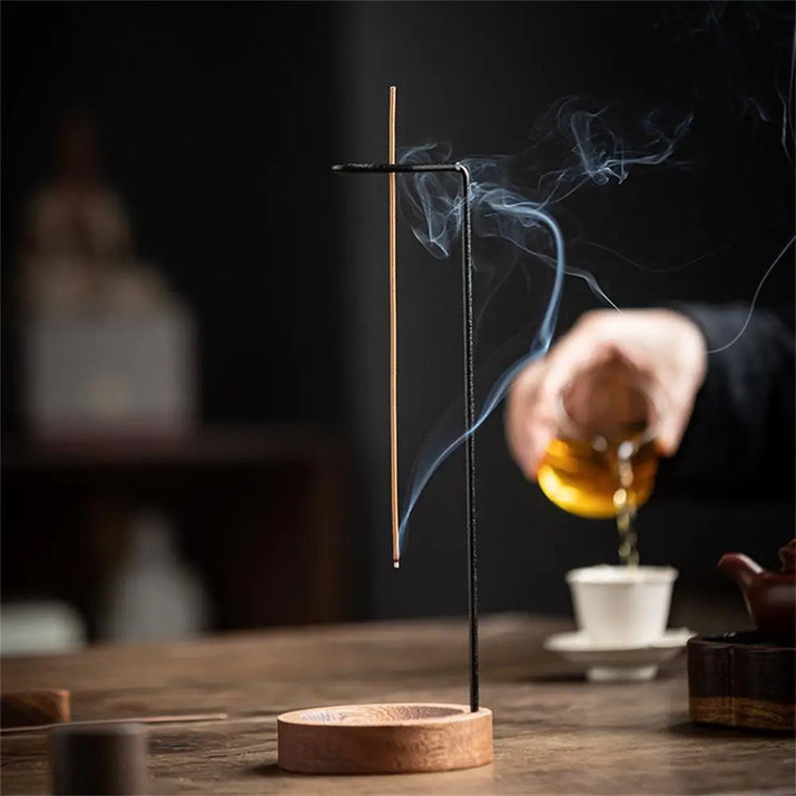Incense stick with smoke on a wooden stand, blurred background